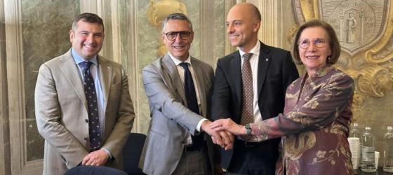 Sparkle, UniGe, and SubOptic sign the deal. Three men and a woman shake hands. In the background a university history classroom