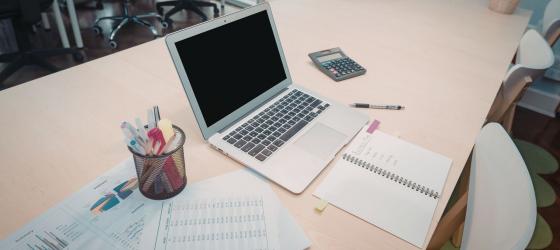 Università della California – Berkeley (USA) – A clean and organized office with a laptop, documents, pens, and a calculator, ready for work